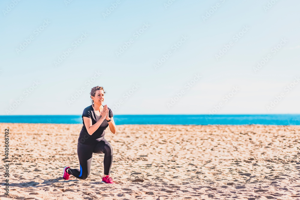 Middle aged woman doing exercise on the beach