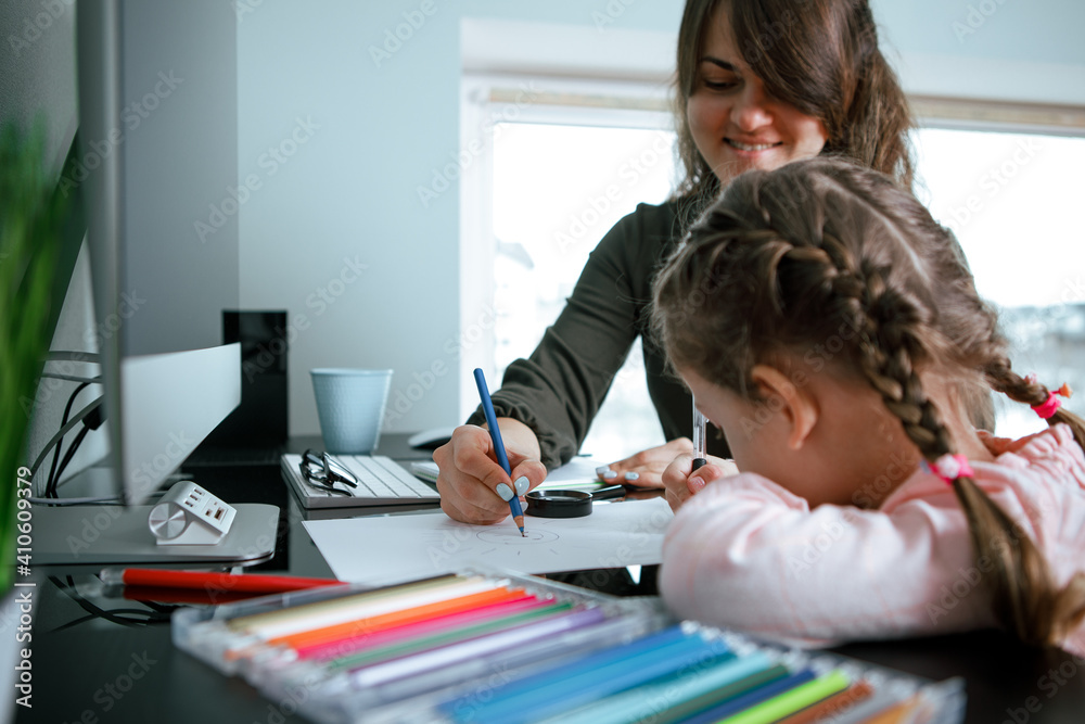 mother and little girl coloring with crayons while sitting together at their living table. early development concept. mother and little girl coloring with crayons while sitting together at their living table. early development concept.