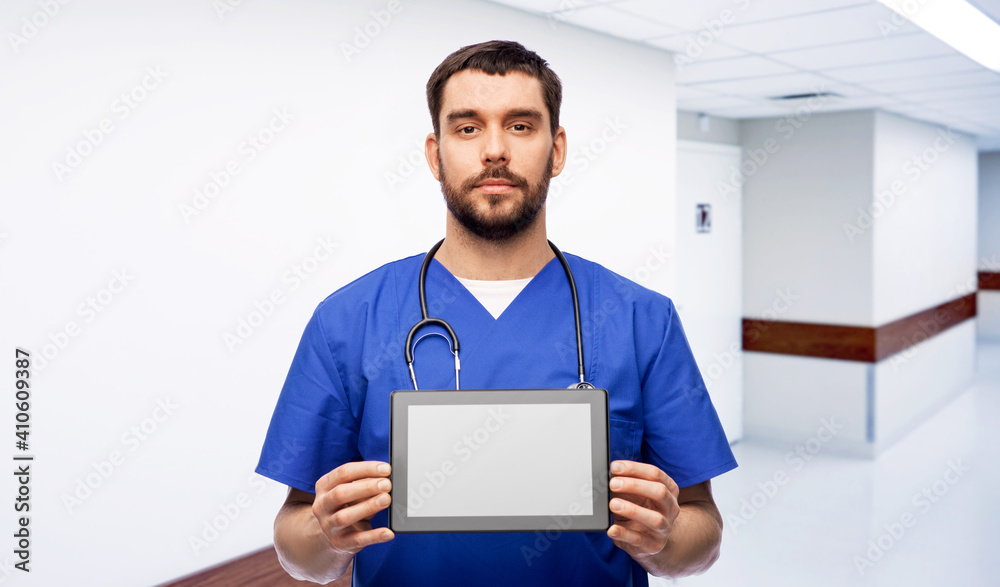 medicine, healthcare and technology concept - doctor or male nurse in blue uniform with stethoscope showing tablet pc computer over hospital corridor on background medicine, healthcare and technology concept - doctor or male nurse in blue uniform with stethoscope showing tablet pc computer over hospital corridor on background