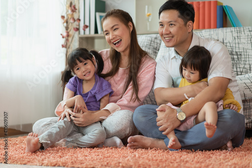 Happy Asian family mother and father with two daughters playing at home