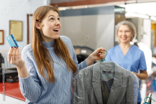 Female customer paying with bank card for service at dry-cleaning salon