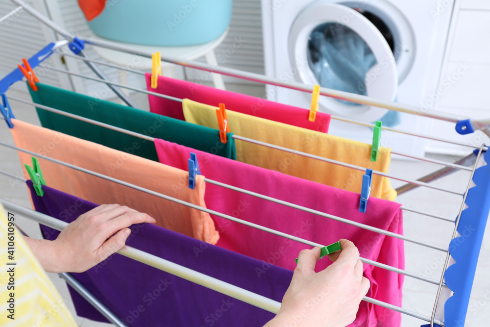 Naklejka premium Woman hanging clean laundry on drying rack indoors, closeup