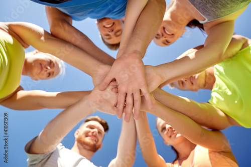 fitness, sport and healthy lifestyle concept - group of happy sporty friends stacking hands outdoors