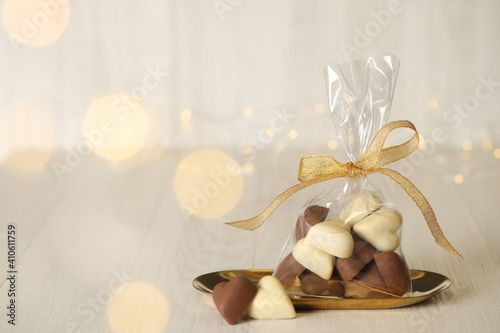 Heart shaped chocolate candies on white wooden table. Space for text