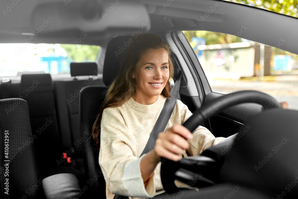 safety and people concept - happy smiling young woman or female driver driving car in city