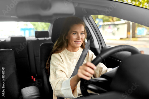 safety and people concept - happy smiling young woman or female driver driving car in city