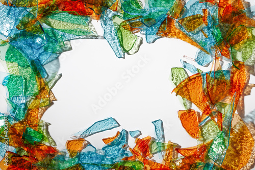 Background of fragments of colored multicolored glass with an iridescent sheen and  with blurred reflections on white background .