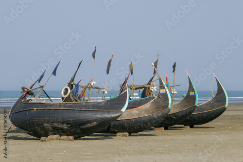 Four traditional wooden fishing boats known as moon boats resting dry on a beach near Cox's Bazar in southern Bangladesh photo