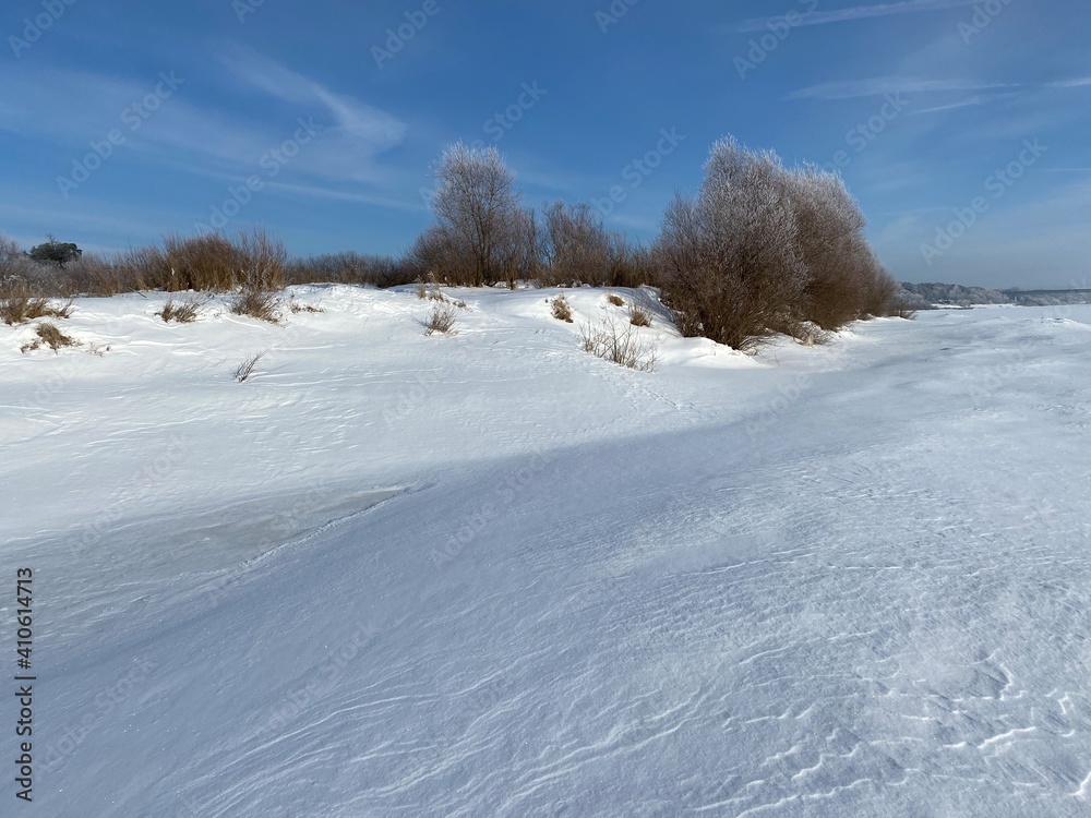 Winter landscape. Sunny day. Blue sky. In a snowy field, the outlines of trees and bushes. Winter landscape. Sunny day. Blue sky. In a snowy field, the outlines of trees and bushes.