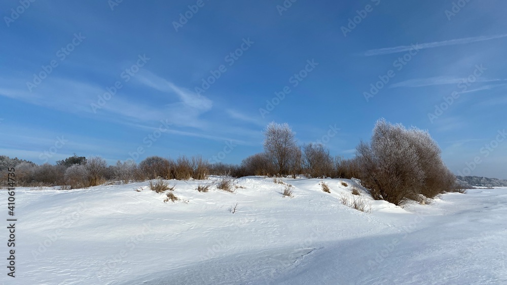 Winter landscape. Sunny day. Blue sky. In a snowy field, the outlines of trees and bushes. Winter landscape. Sunny day. Blue sky. In a snowy field, the outlines of trees and bushes.