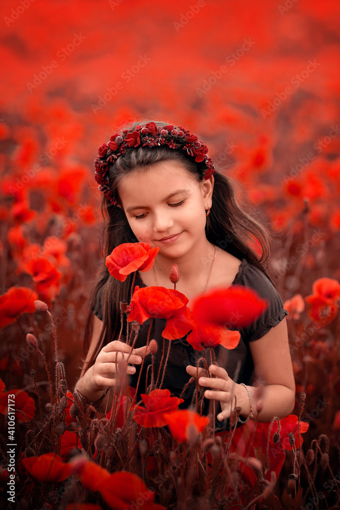 small girl with a wreath on her head in a brown dress on a poppy field ...