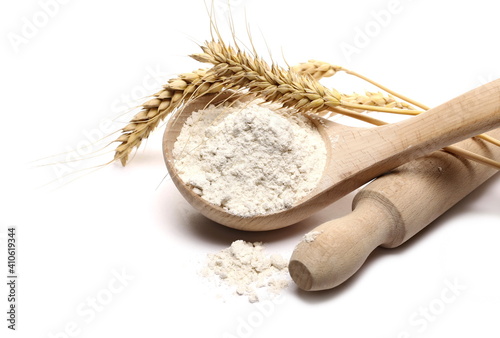 Rye flour, wheat ears with wooden spoon and kitchen rolling pin isolated on white background