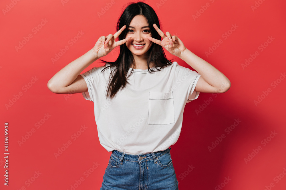 Charming woman in stylish T-shirt smiles and shows peace signs Charming woman in stylish T-shirt smiles and shows peace signs