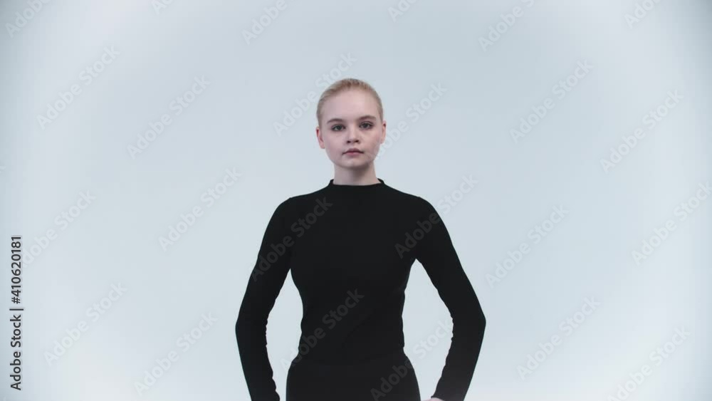 Gymnastics - young woman raising up her leg against her body and holding it - looking in the camera Gymnastics - young woman raising up her leg against her body and holding it - looking in the camera