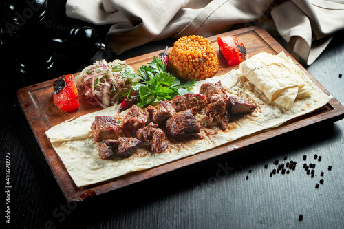 Grilled beef fillet with bulgur and vegetables garnished on a wooden board. Turkish kebab. Close up, selective focus