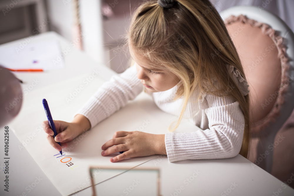 Little girl sitting in her room and writing. Little girl sitting in her room and writing.
