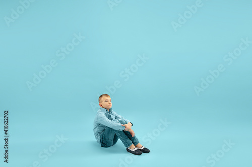 Dreaming. Childhood and dream about big and famous future. Pretty little boy isolated on blue studio background. Childhood, dreams, imagination, education, facial expression, emotions concept.