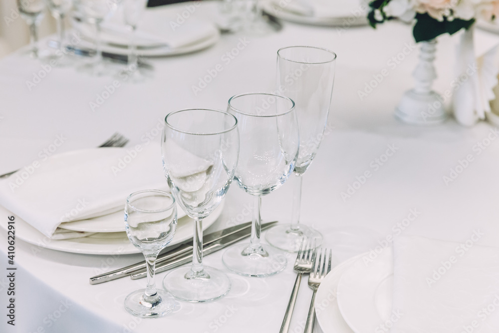 Fancy table set for dinner with napkin glasses in restaurant, luxury interior background. Wedding elegant banquet decoration and items for food arranged by catering service on white tablecloth table.