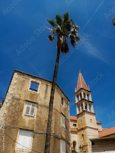 Church, old apartment buildings and palm trees of Milna on island of Brač.

Milna, Croatia - July 26th 2020