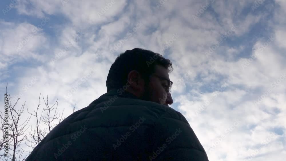 Religious young man displays reverence to God, with cloudy blue sky