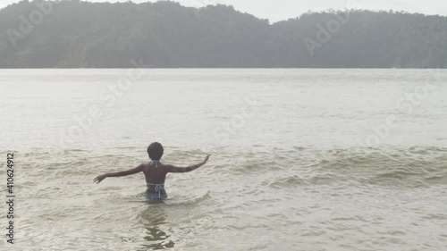 Girl dancing and enjoying herself in the waters of the north coast of Trinidad photo