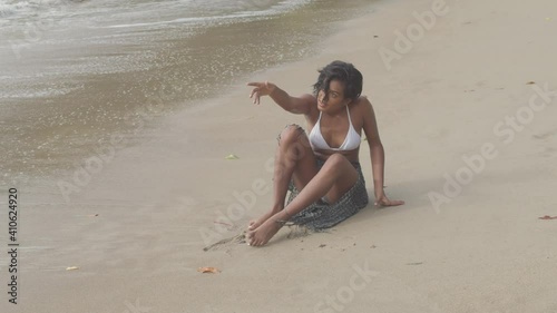 Sexy girl in a bikini sitting in the sand before standing up photo