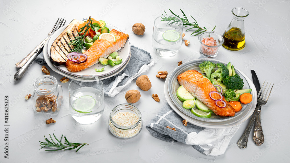 Two portions of homemade fresh salmon with vegetables on a light background.