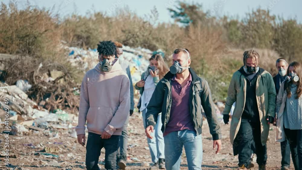 Sad Young Volunteers in Gas Masks Going Through the Garbage Dump. The Concept of Problem of Recycle of Trash. Environmental Pollution Sad Young Volunteers in Gas Masks Going Through the Garbage Dump. The Concept of Problem of Recycle of Trash. Environmental Pollution