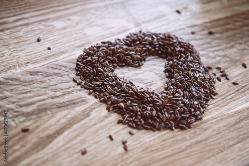 Flax seeds in a heart shaped on wooden background. Side view