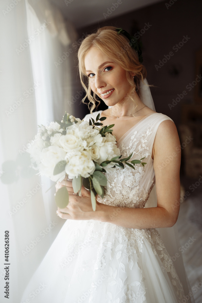 Naklejka premium Beautiful bride portrait in wedding dress near window