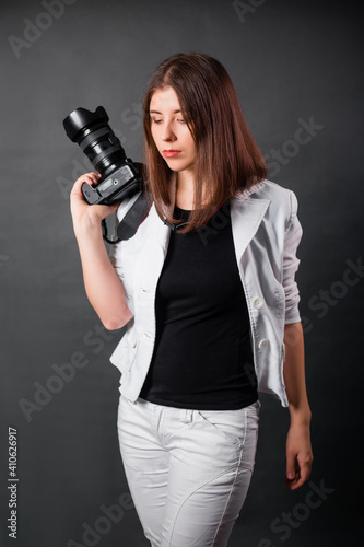 Woman photographer with a SLR camera in her hands posing on a gray background. © Михаил Гута