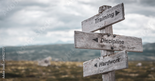 training discipline hardwork text engraved on wooden signpost outdoors in nature. Panorama format. photo