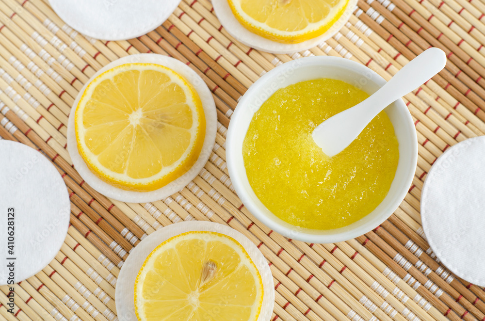 Homemade lemon fruit scrub (bath salt, foot soak, facial or hair mask) in a  small white bowl and cotton pads. Natural beauty treatment and spa recipe.  Top view, copy space. Stock Photo |