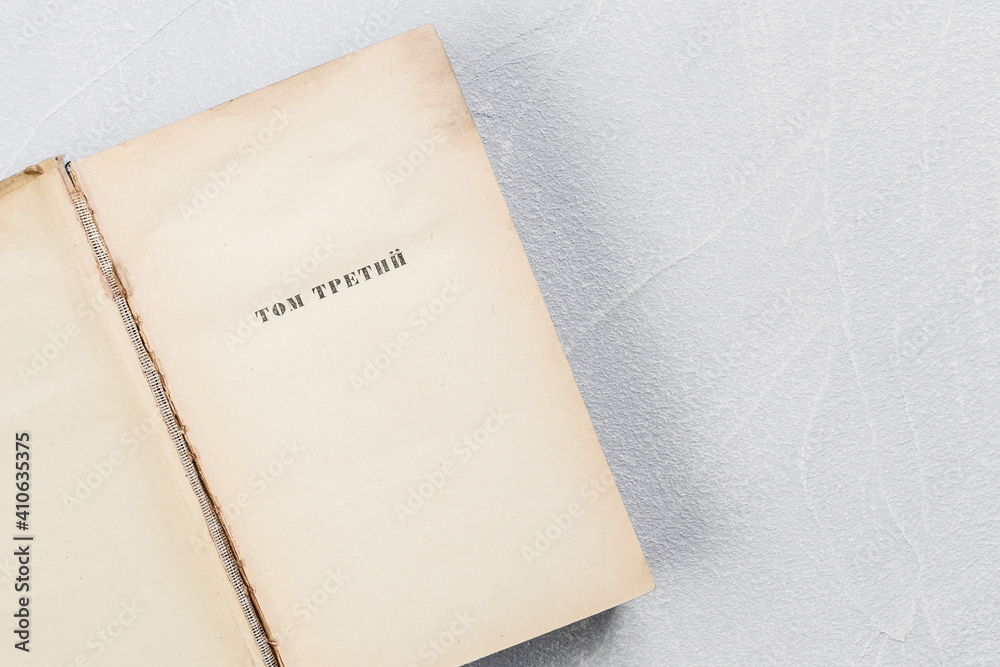 Page of an open old shabby yellowed book with blank sheets of vintage paper with the inscription in Russian Volume Three