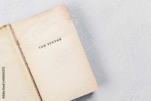 Page of an open old shabby yellowed book with blank sheets of vintage paper with the inscription in Russian Volume Three