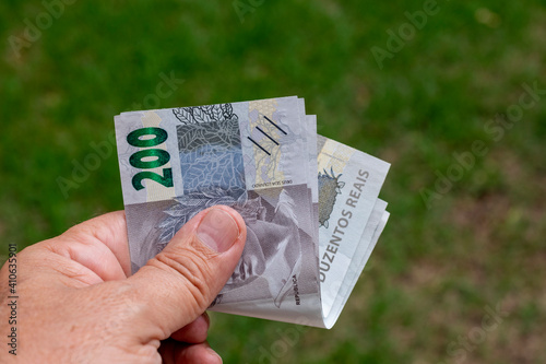 man holding Brazilian money bills with green defocused background. photo