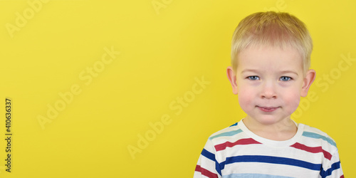 Happy smiling little boy on color background. Portrait of a beautiful European boy two years old on a yellow background. Copy space for text.