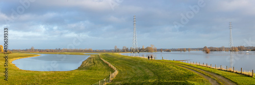 Wide panoramic landscape with the river IJssel overflowing its boundaries into floodplains with a winter dyke making its way trough the high water levels