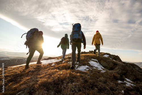 Hikers with backpacks walks in mountains at sunset photo