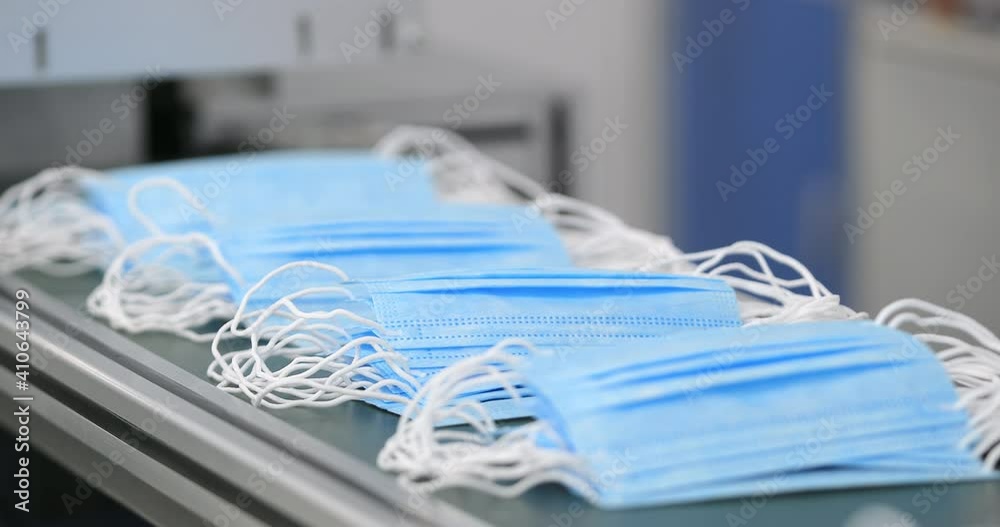 Covid protection. Manufacture of surgery face mask. Worker in protective suit sorts masks for sending to medical facilities. Production of disposable medical clothing for protection against the virus. Covid protection. Manufacture of surgery face mask. Worker in protective suit sorts masks for sending to medical facilities. Production of disposable medical clothing for protection against the virus.