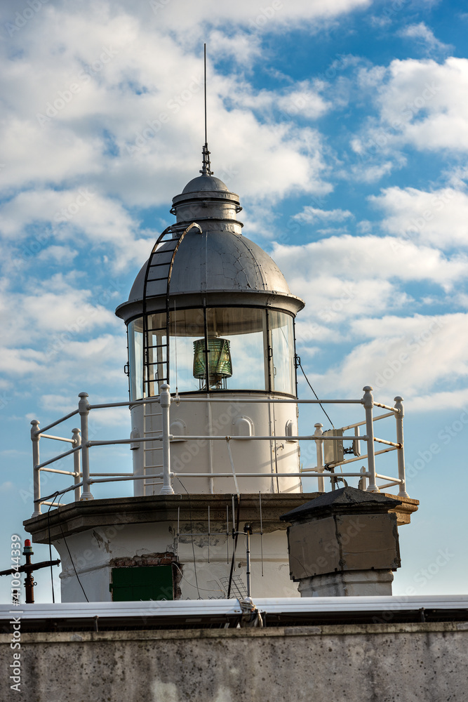 Closeup of the old white lighthouse on blue sky with clouds in the port of Portofino, Genova province, Liguria, Italy, Europe.