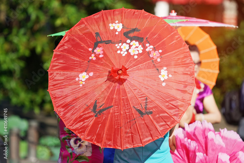 Chinese Women in Native Dress Hold an umbrella standing beside lotus lake