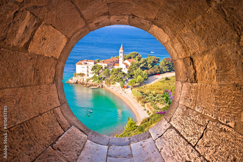 Bol on Brac island. Monastery on pebble beach in Bol view through stone window