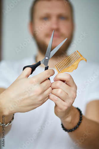 A male hairdresser wih bread holds scissors and a comb in his hands  barbershop