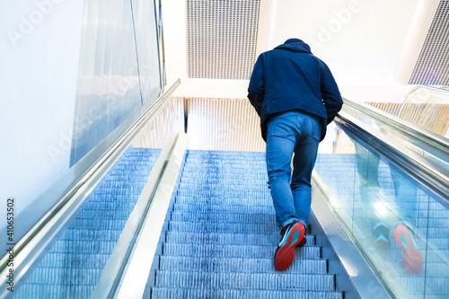 Blurred back view man going up the escalator. Young man going up the escalator