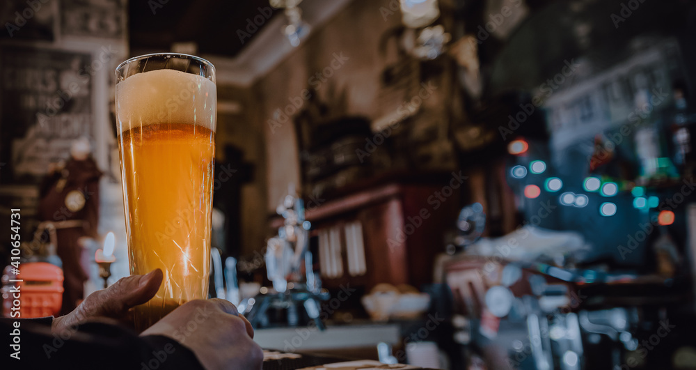 man holds a glass of beer in his hand at the bar or pub