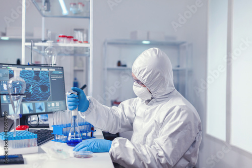 Medical researcher measuring liquid using automatic pipette in micriobiology lab. Chemist in modern laboratory doing research using dispenser during global epidemic with covid-19.