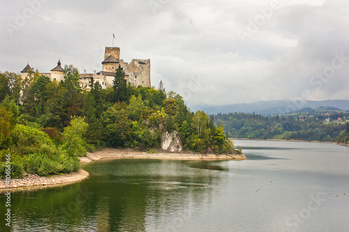 Ancient castle Dunajec in Nedzice, Poland, Europe. Landscape with an old castle on a hill above the lake on a cloudy day.
