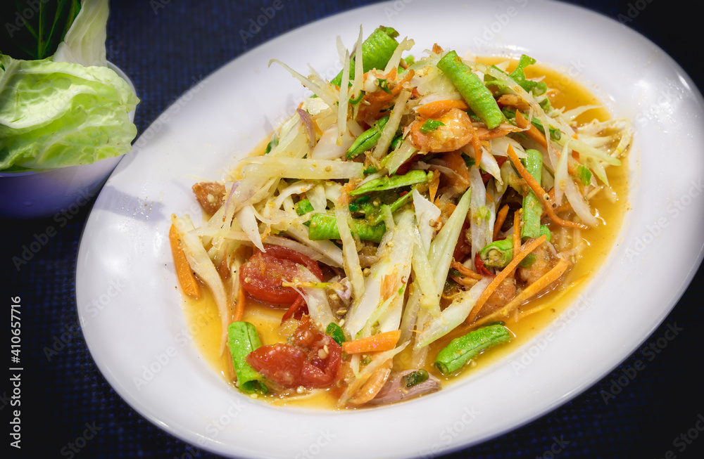 Cropped shot of Somtum or papaya salad, Thai traditional food with sticky rice, chicken grilled and cutlery on rustic table Cropped shot of Somtum or papaya salad, Thai traditional food with sticky rice, chicken grilled and cutlery on rustic table