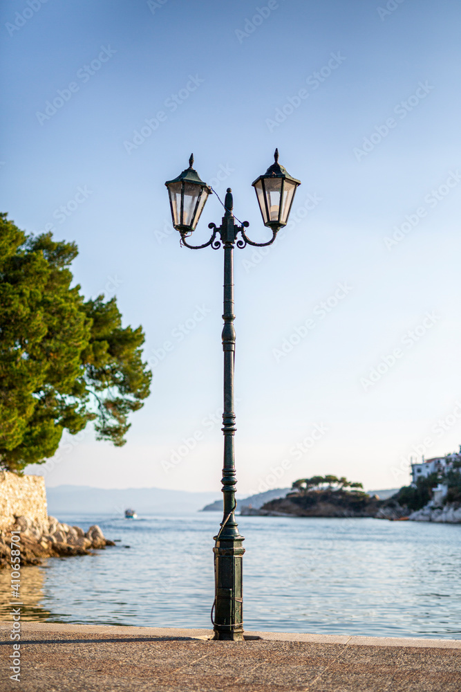 Single street lamp on the pier seafront with flowing water at sunset.